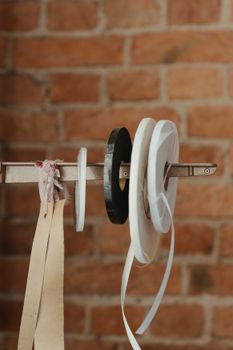 Ribbons and tape reels against a rustic brick wall ideal for craft and sewing projects.