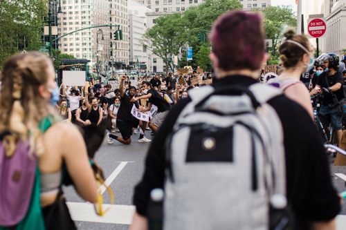 Free A diverse group of people gathered in a city street for a protest, raising fists in solidarity. Stock Photo