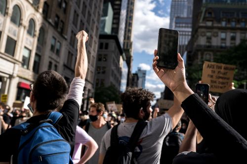Free A diverse group of protesters in a city holding signs and raising fists emphasizing social justice. Stock Photo