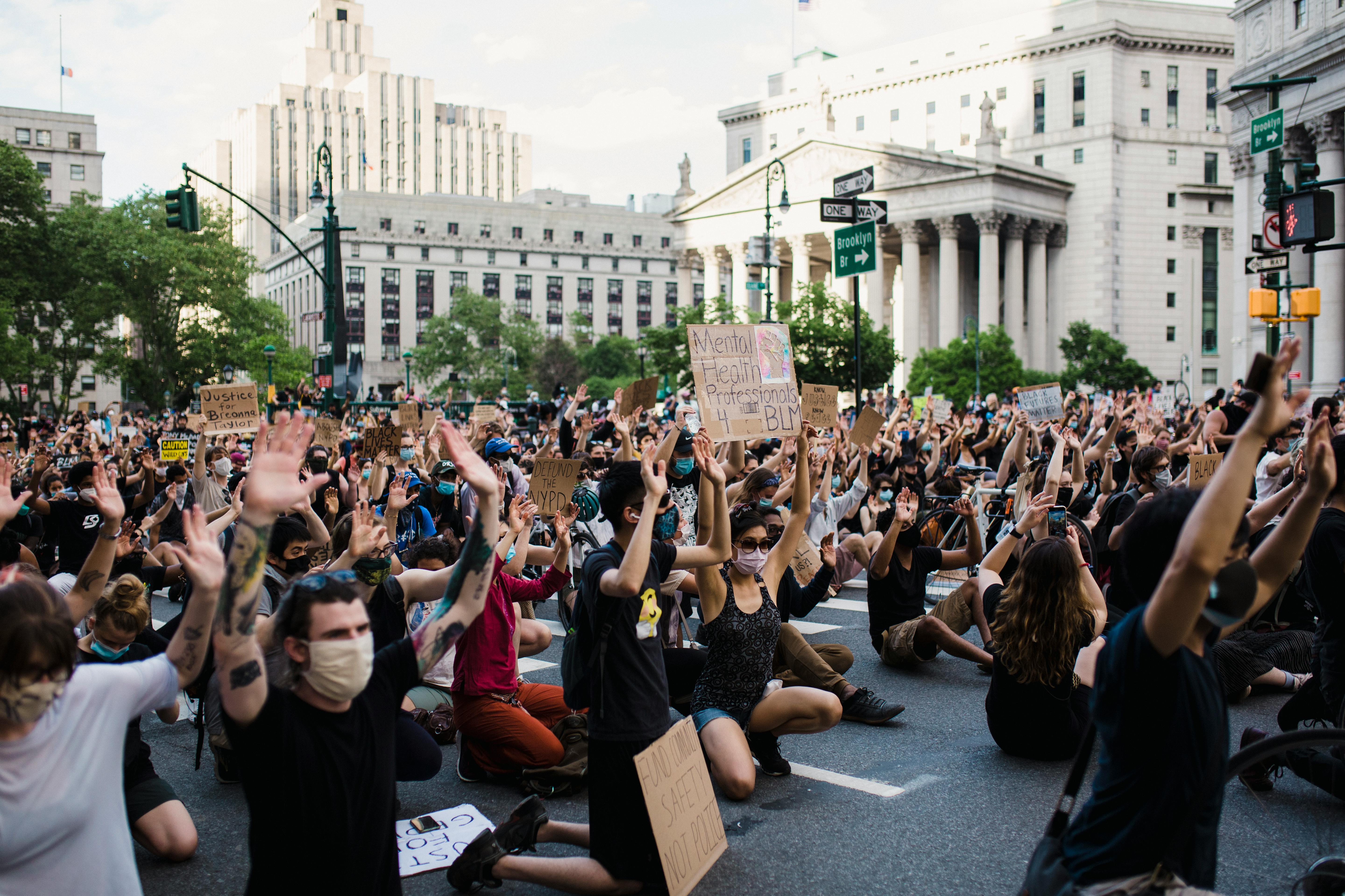 crowd of protesters holding signs and kneeling