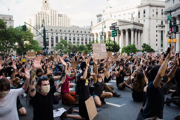 Crowd Of Protesters Holding Signs And Kneeling