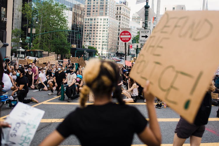 Crowd Of Protesters Holding Signs And Kneeling