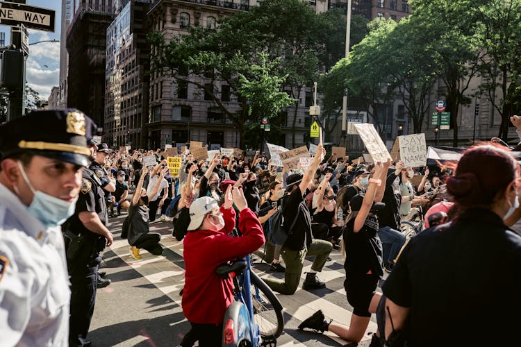 Crowd Of Protesters Holding Signs And Kneeling