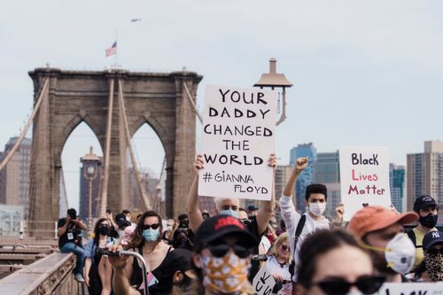 Free Crowd protests racial injustice on Brooklyn Bridge, holding signs for change. Stock Photo