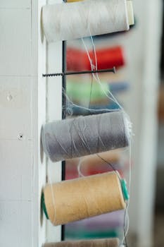 Close-up of various colors of sewing thread spools neatly organized along a wall.