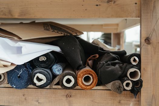 Close-up of diverse fabric rolls neatly arranged in an artisanal workshop setting.