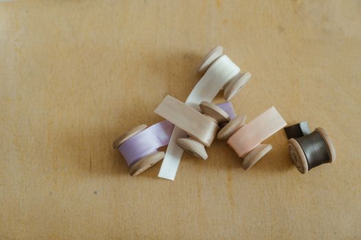 A variety of colored ribbon spools neatly arranged on a wooden surface shot from above.
