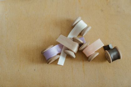 Wooden spools of satin ribbon in soft pastel shades, photo by cottonbro studio on Pexels