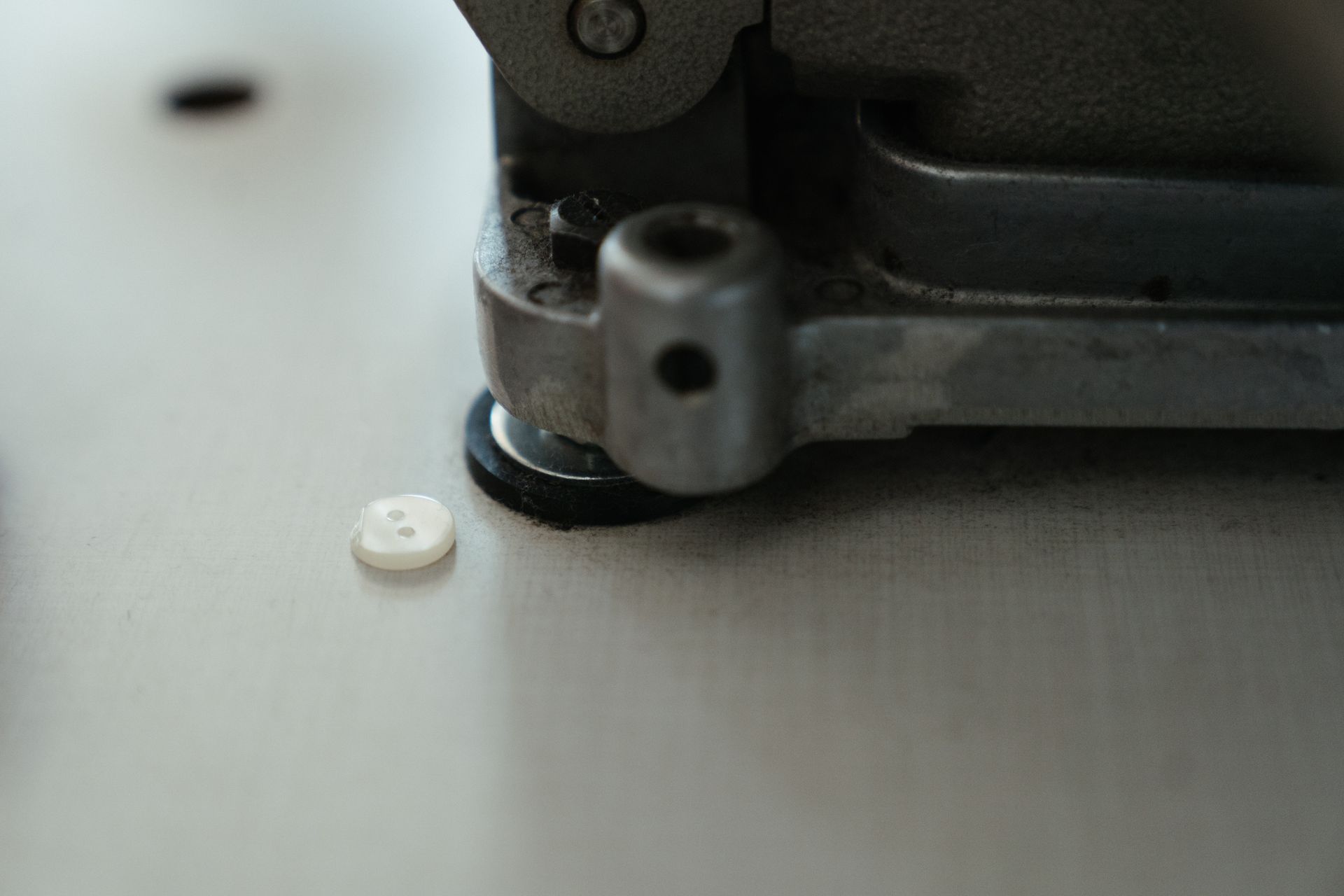 Detailed view of a button next to a sewing machine component in a workshop setting.