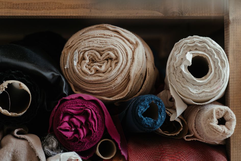 Cuộn vải nhiều màu sắp xếp trong xưởng may, lựa chọn nguyên liệu đúng loại tăng hiệu quả sản xuất