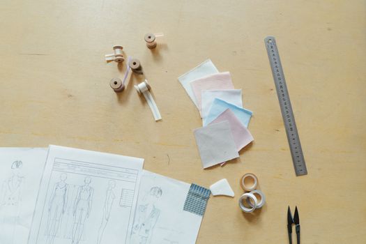 Flat lay of sewing tools and fabric samples in a fashion design studio.