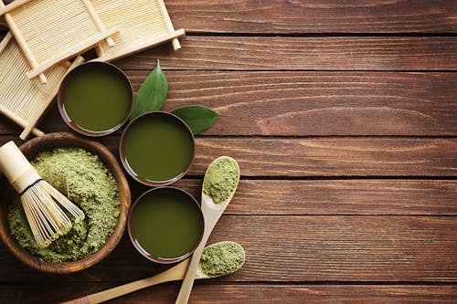 Bowl of Green Powder on Brown Wooden Surface