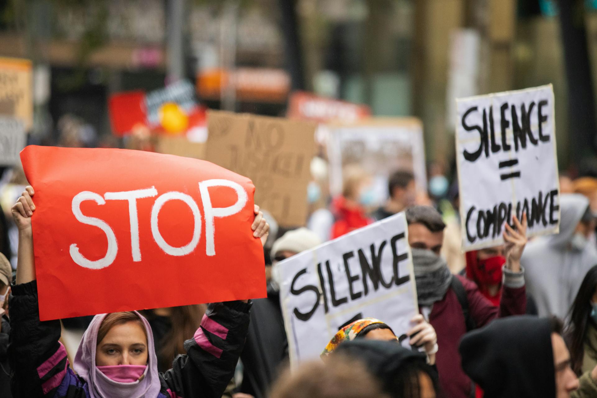 Woman in Pink Hijab Holding Red Poster with Stop Message