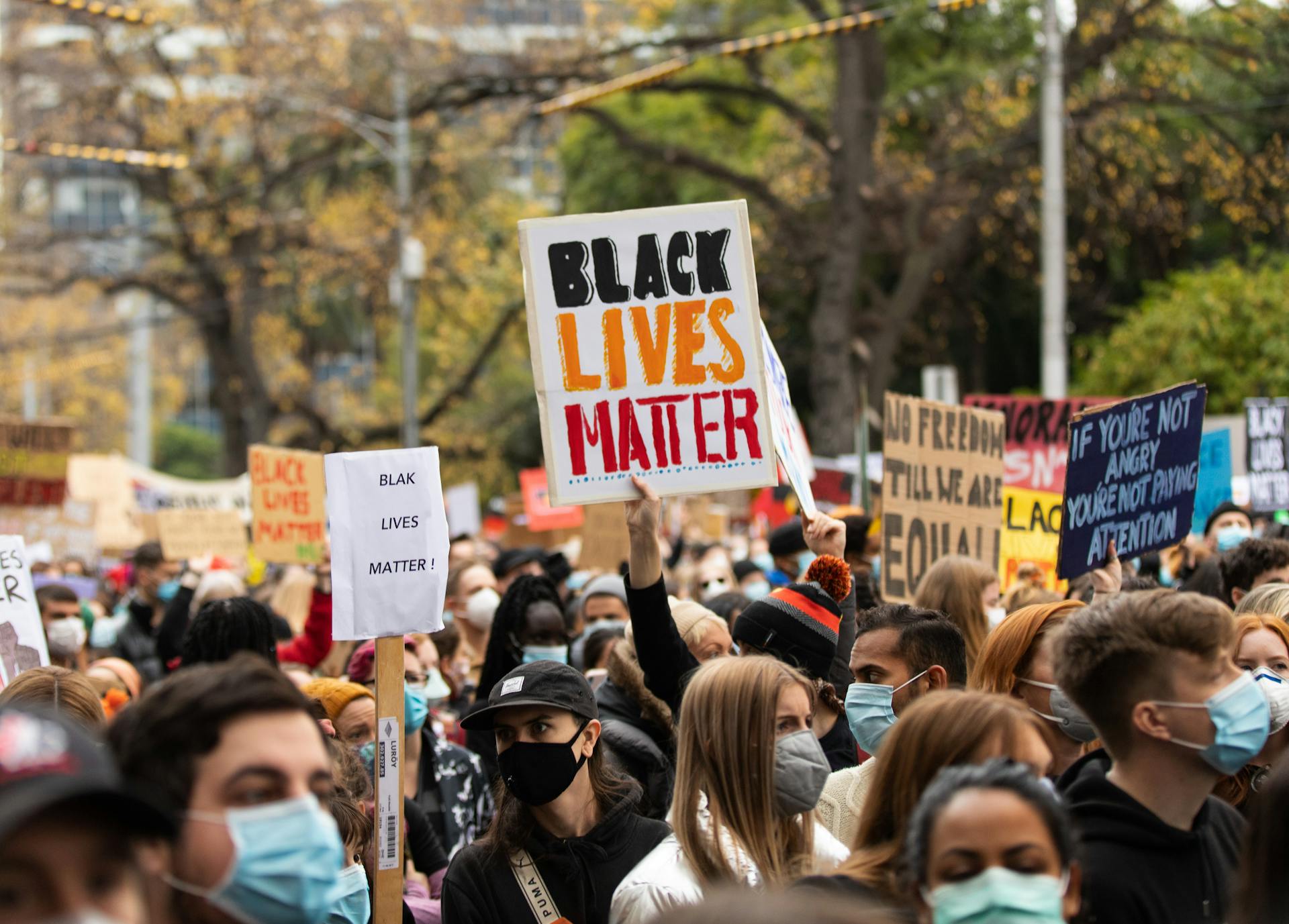 A diverse crowd protests in Melbourne with Black Lives Matter signs.
