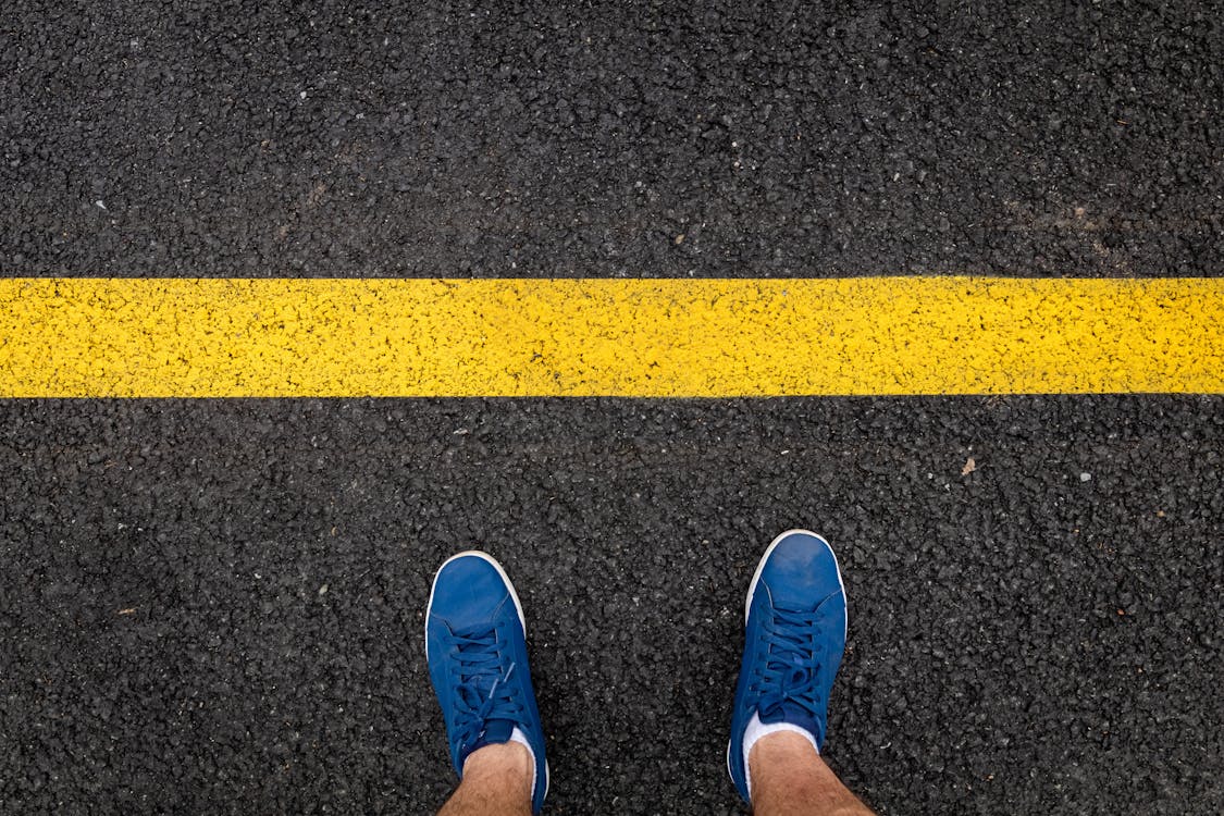 Free A Person Wearing Blue Shoes on an Asphalt Road Stock Photo