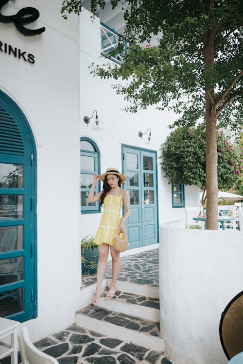 Free Stylish Asian woman in bright sundress walking on stairs outdoors Stock Photo