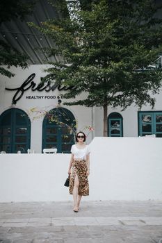 一位穿着时髦、戴着太阳镜的严肃女性，在城市街道的咖啡馆附近漫步，展望未来