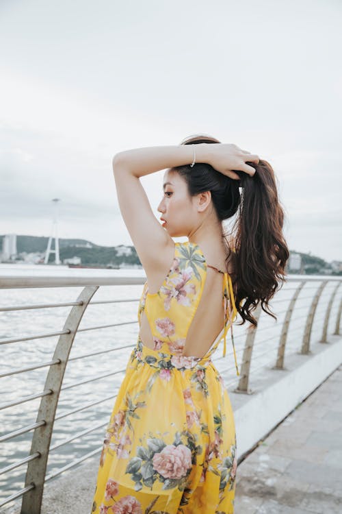 Pensive Asian woman in casual dress near railing
