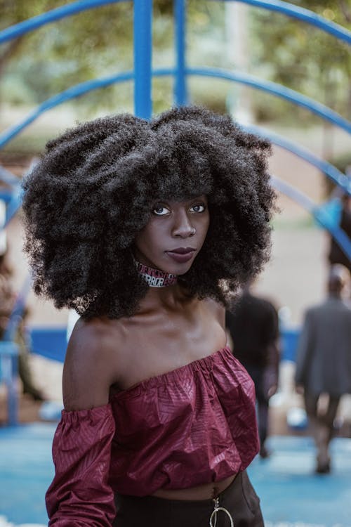 Stylish black woman with Afro hairstyle near wall on street · Free