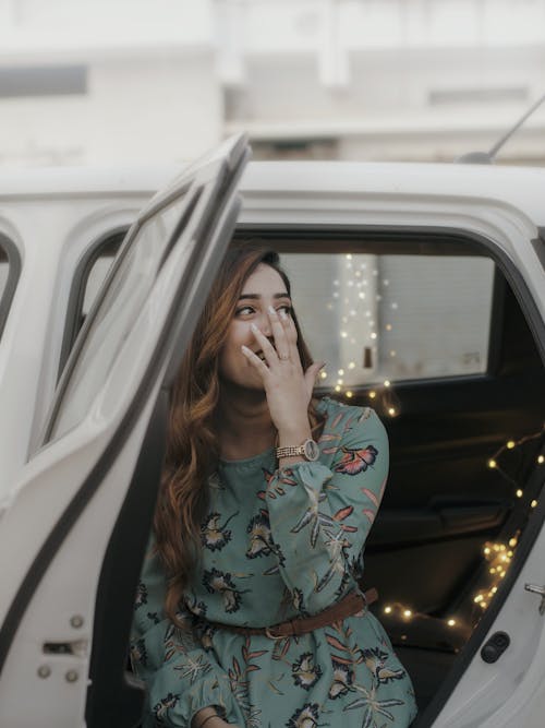 Free Woman in White and Black Floral Long Sleeve Shirt Sitting on White Car during Night Time Stock Photo