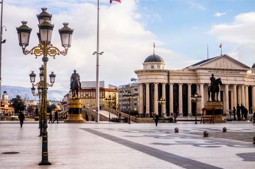 Free Tiled square with equestrian statues near lanterns and aged building facade with columns in Yugoslavia Stock Photo