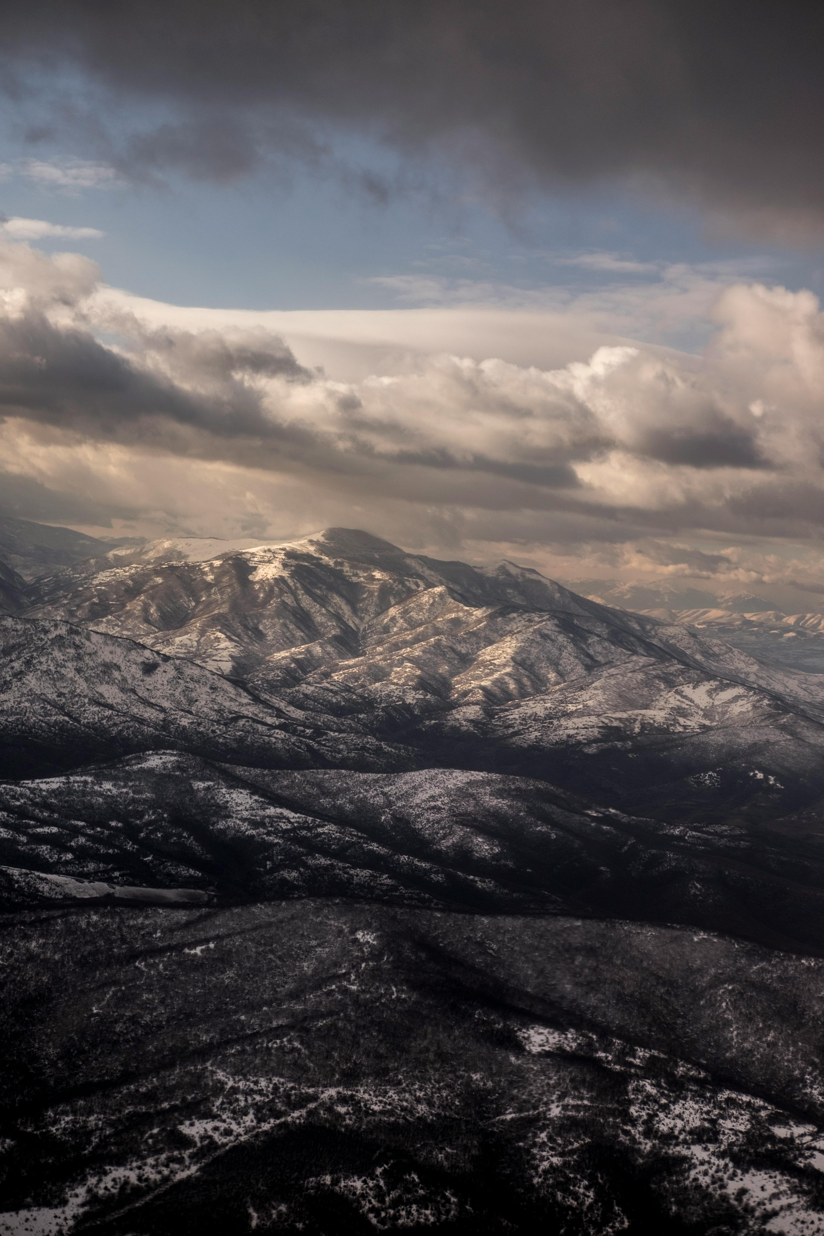 rough snowy mountains under cloudy sky at night