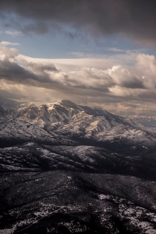 Rough snowy mountains under cloudy sky at night