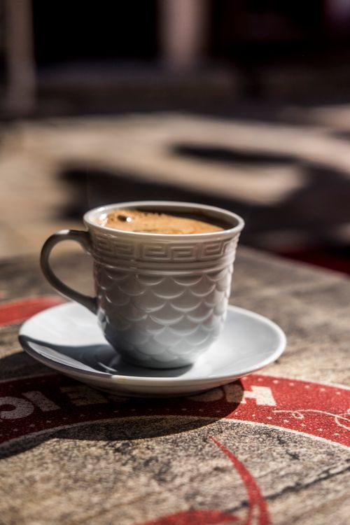 Free White ornamental cup of hot coffee with foam and bubble on surface on shabby table Stock Photo