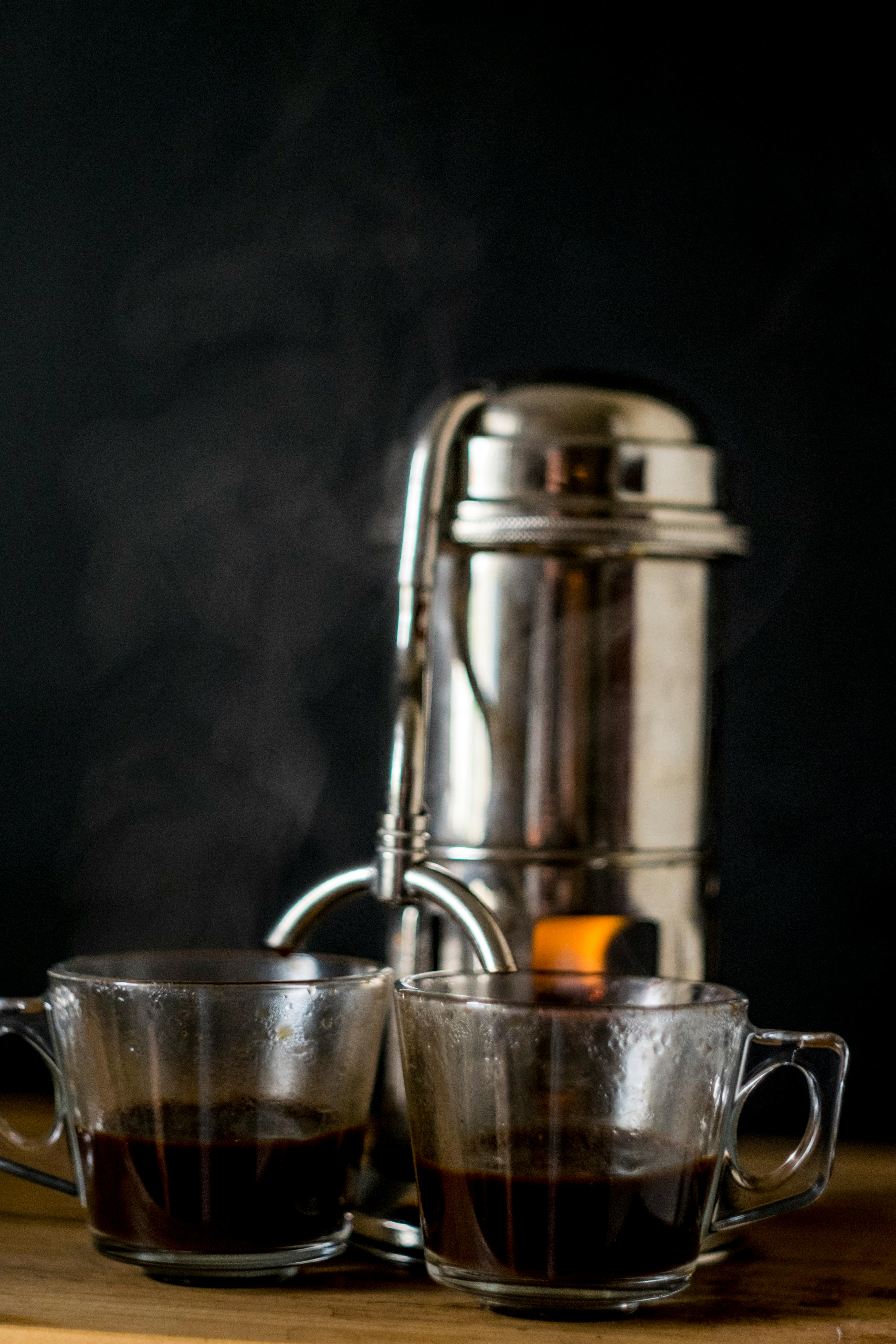 metal coffee maker with glass cups on table