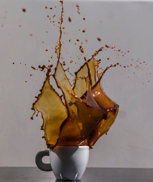 Cup with fast coffee fluid in air on white background