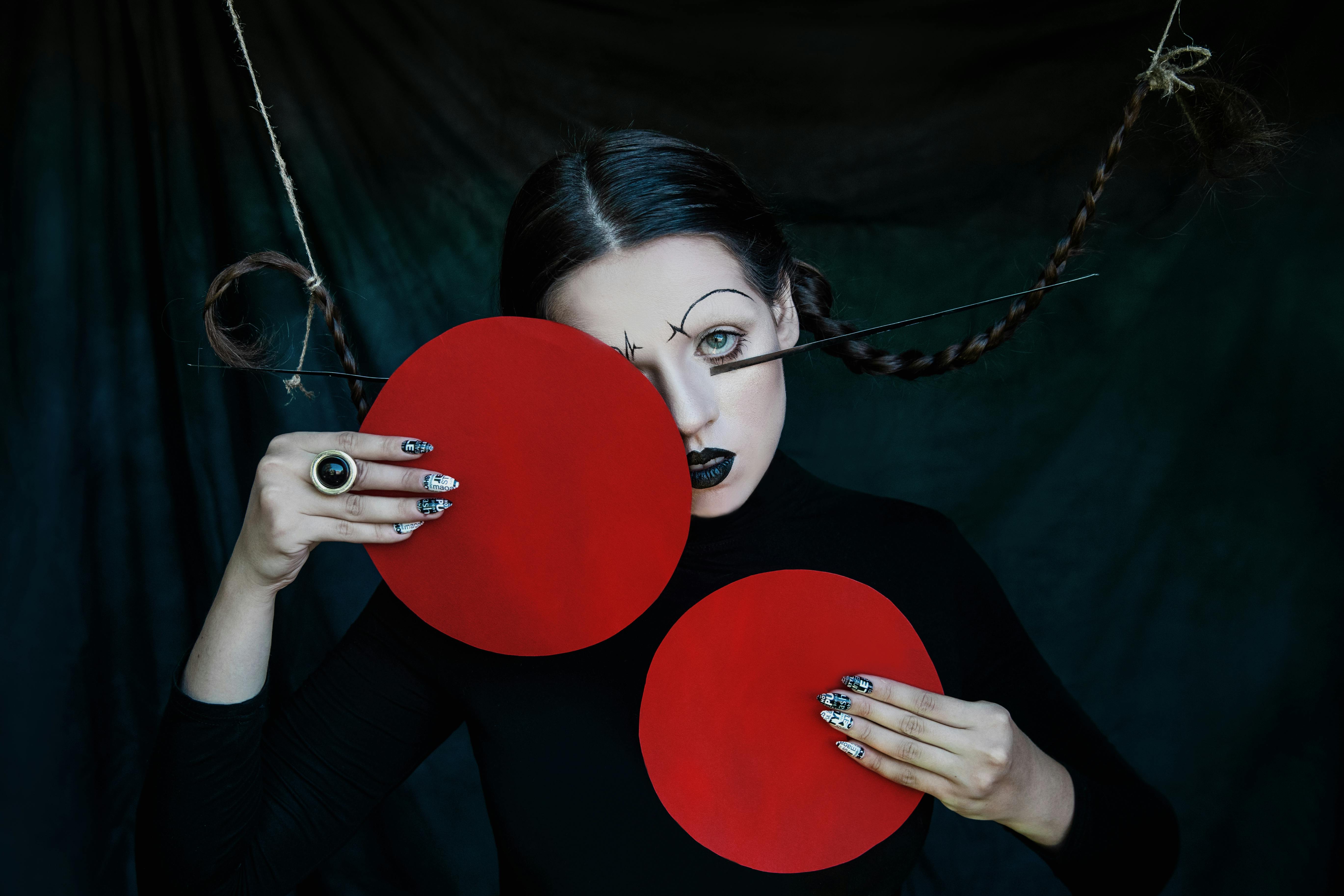 这幅艺术肖像富有戏剧性，描绘了一位妆容独特、扎着辫子的女子，在黑暗背景中被打上了红圈