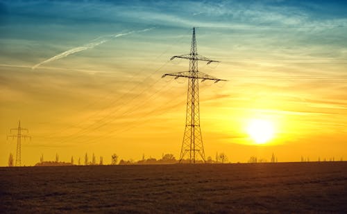 Brown Transmission Towers on Field during Sunset Landscape Photography