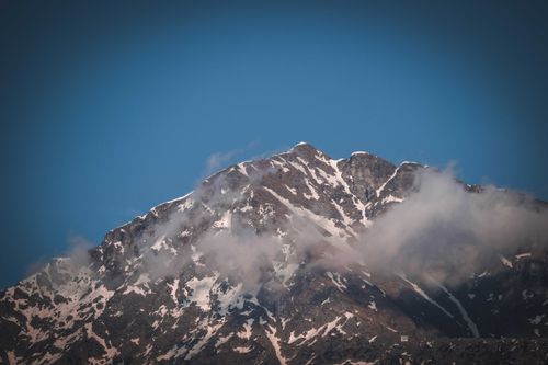 Free Severe scenery of rough rocky mountain with slopes covered with snow under cloudless blue sky Stock Photo
