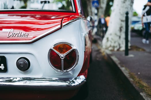 Close-up of a vintage red Cortina car parked on a street showing its classic design.