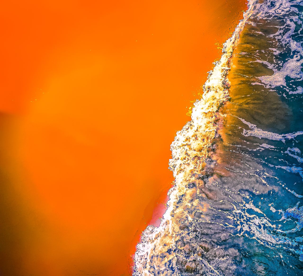 dynamic aerial view of ocean waves meeting vibrant orange sand at virg