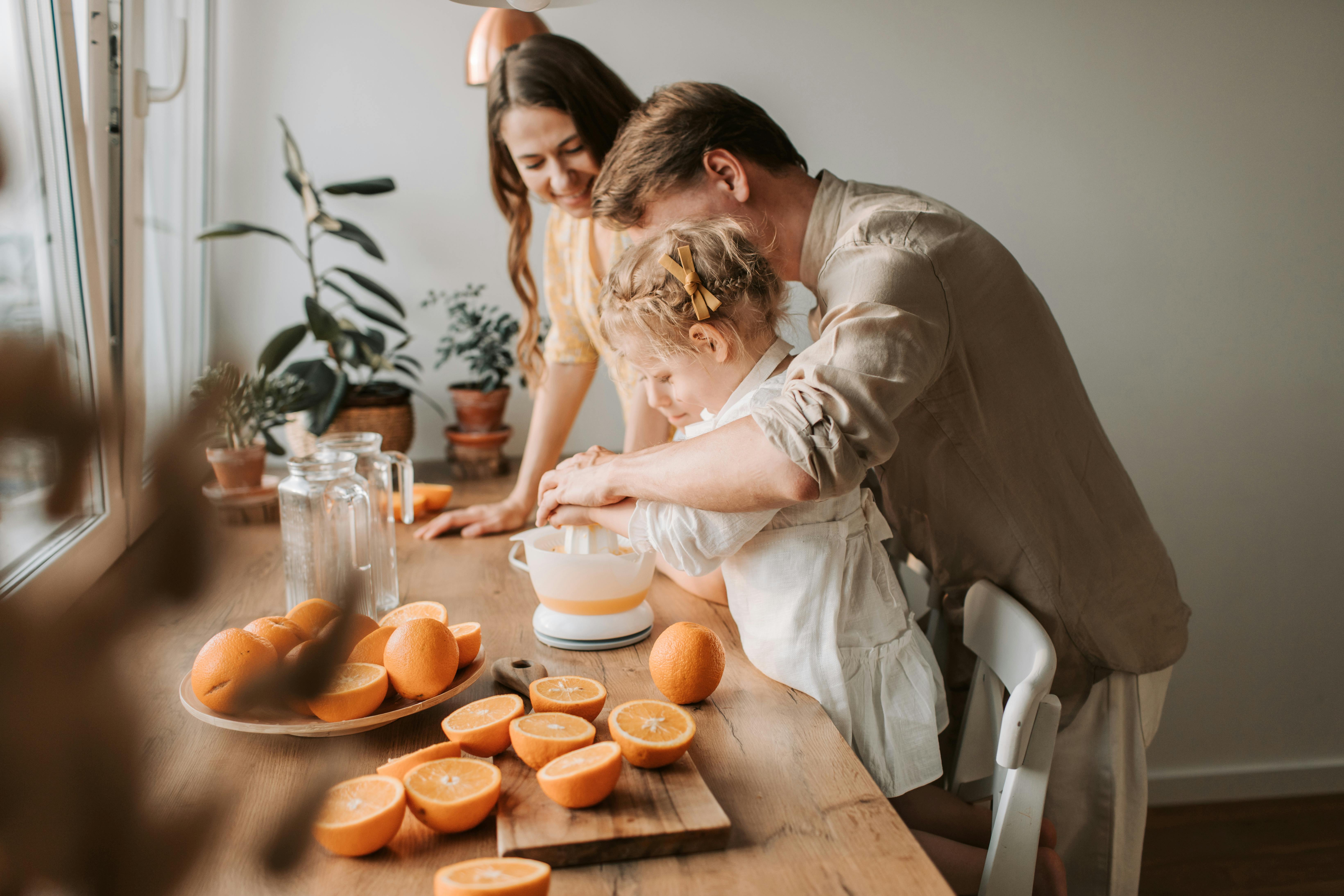 A family enjoys making fresh orange juice together in a warm and inviting kitchen setting.