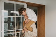 父亲在室内扛着儿子，享受快乐的家庭时光