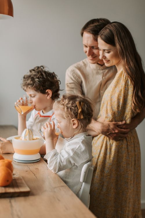 Free A joyful family moment with parents and kids drinking freshly squeezed orange juice indoors. Stock Photo