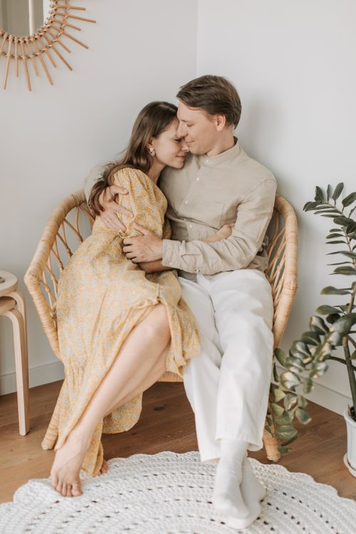 Free A couple sharing a tender embrace while sitting on a wicker chair indoors, expressing love and connection. Stock Photo