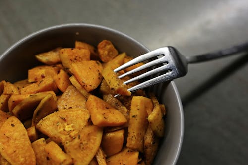 Free From above yummy organic sweet potato fried with herbs and seasonings served in bowl with fork Stock Photo
