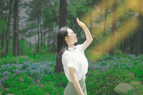 A Woman in White Shirt Raising Her Hand with Her Eyes Closed