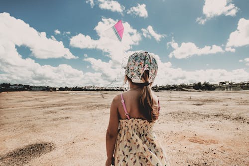 Free Anonymous child flying kite on beach on sunny day Stock Photo