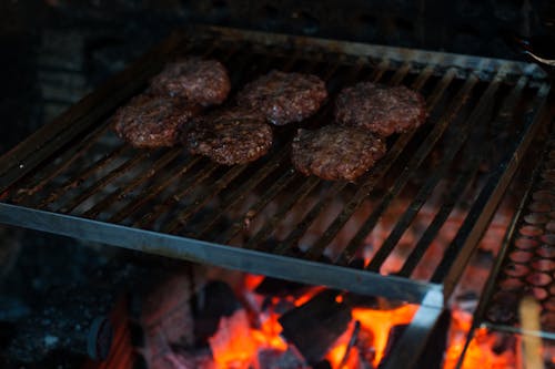 Free High angle of yummy meat cutlet preparing on barbecue barbecue grid placed over burning flame during picnic Stock Photo