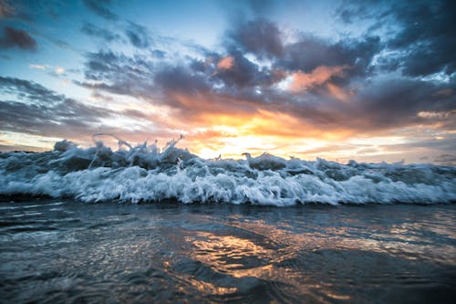 Stormy sea waving on sandy shore at sundown