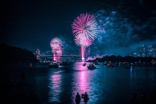 Free Anonymous people in boats floating in river and admiring firework at night Stock Photo