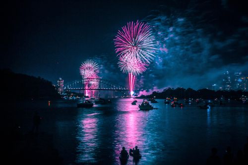 Free Majestic firework in dark night sky over bridge crossing river with various floating boats in modern city Stock Photo