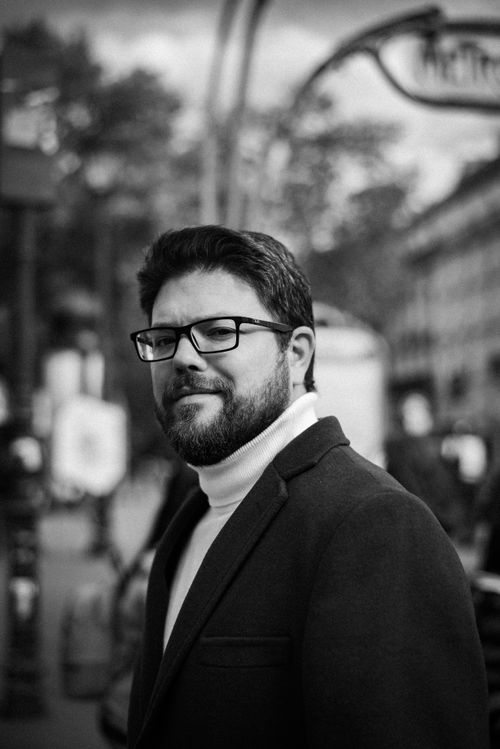 Free Black and white portrait of a bearded man in a suit and turtleneck outdoors. Stock Photo