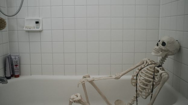 A humorous display of a skeleton relaxing in a bathtub, in a modern bathroom setting. - Fotografer Sidoarjo
