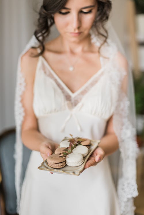 Woman in White Lace Dress Holding White Ceramic Bowl With Pies