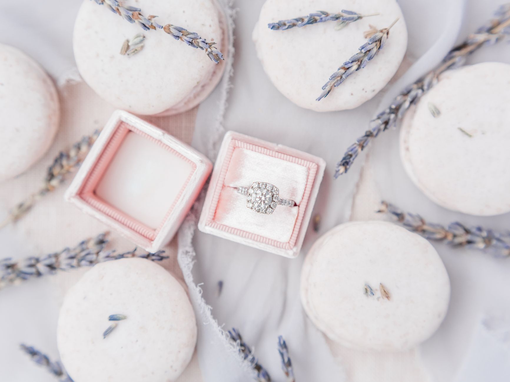 overhead flat-lay of proposal planning details - ring box, handwritten notes, flowers, and a small candle on a wooden surface